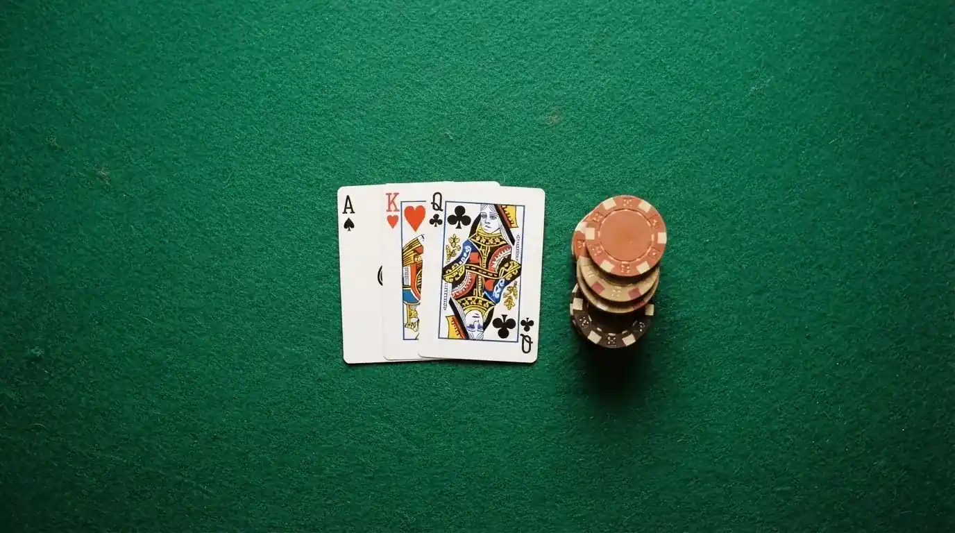 Vista cenital de una baraja de cartas y fichas de casino apiladas sobre una mesa de fieltro verde.